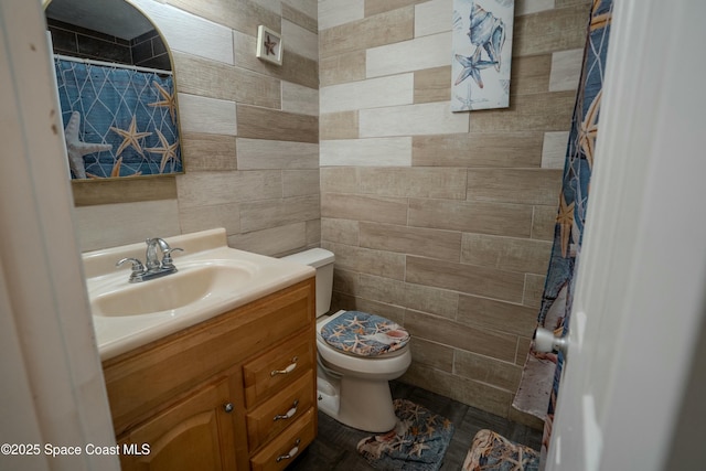 bathroom with vanity, tile walls, and toilet