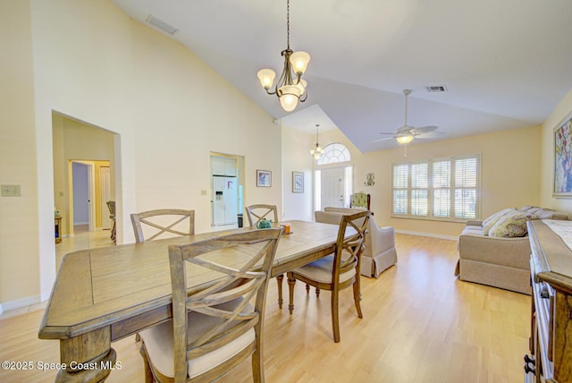 dining room with ceiling fan with notable chandelier, high vaulted ceiling, and light wood-type flooring