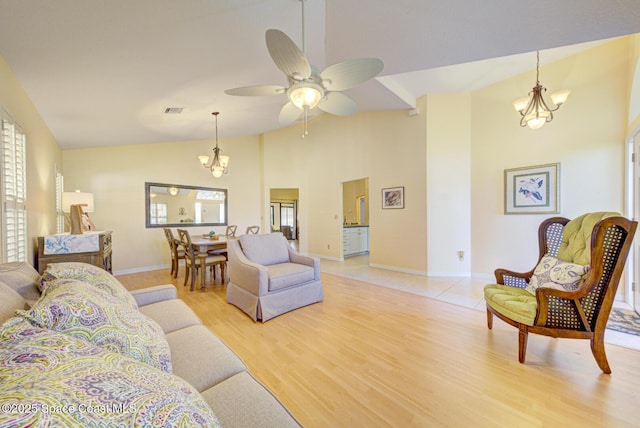 living room featuring ceiling fan with notable chandelier, high vaulted ceiling, and light wood-type flooring