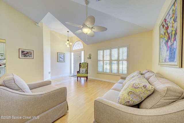 living room featuring ceiling fan with notable chandelier, high vaulted ceiling, and light hardwood / wood-style flooring