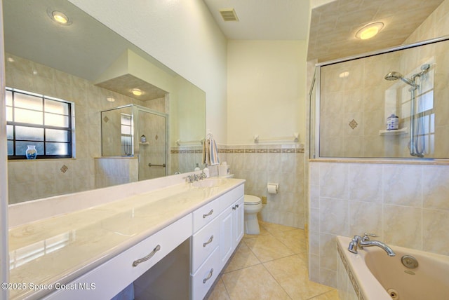 full bathroom with tile walls, vanity, tile patterned floors, shower with separate bathtub, and toilet