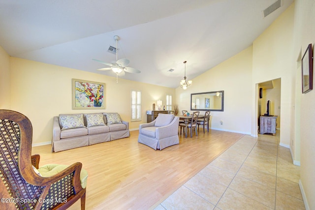 living room featuring ceiling fan with notable chandelier, high vaulted ceiling, and light wood-type flooring