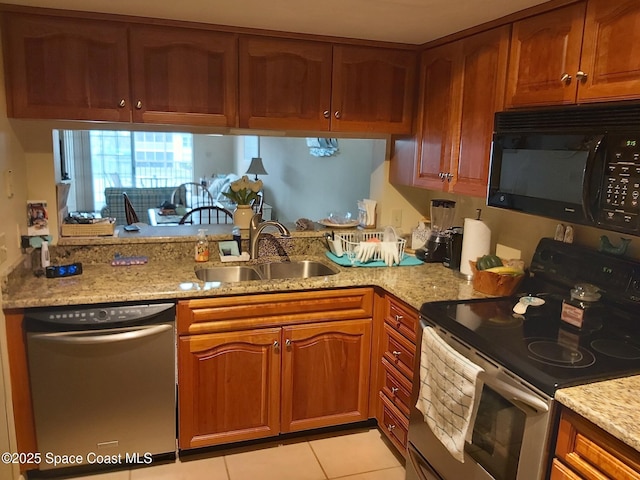 kitchen with sink, light tile patterned floors, light stone countertops, and appliances with stainless steel finishes