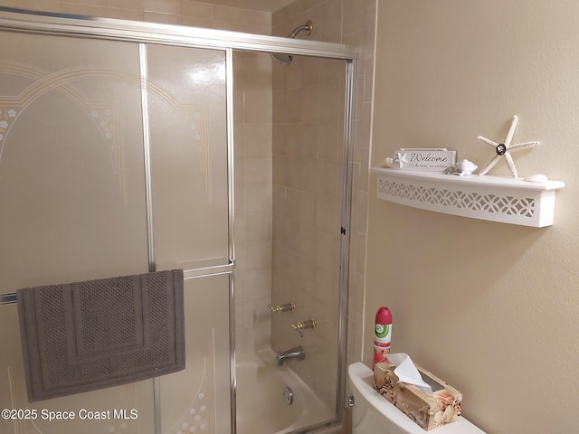 bathroom with shower / bath combination with glass door and toilet