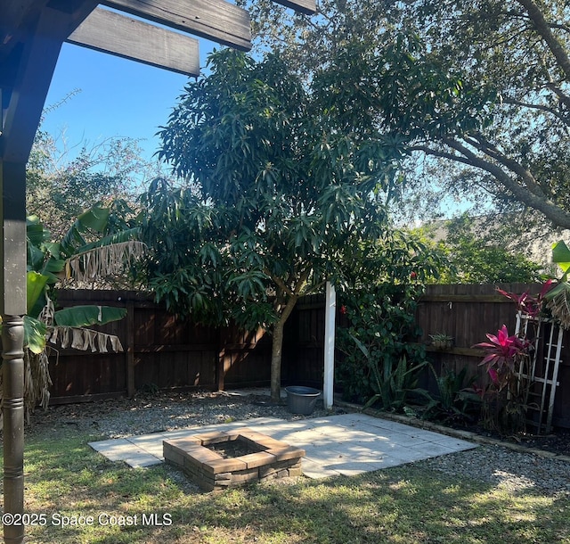 view of yard featuring a patio, a fire pit, and fence