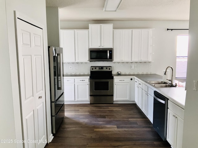 kitchen with dark wood-type flooring, a sink, stainless steel appliances, white cabinets, and decorative backsplash