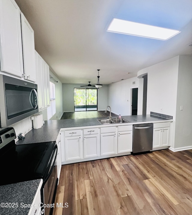 kitchen featuring a sink, stainless steel appliances, white cabinets, and light wood-style flooring