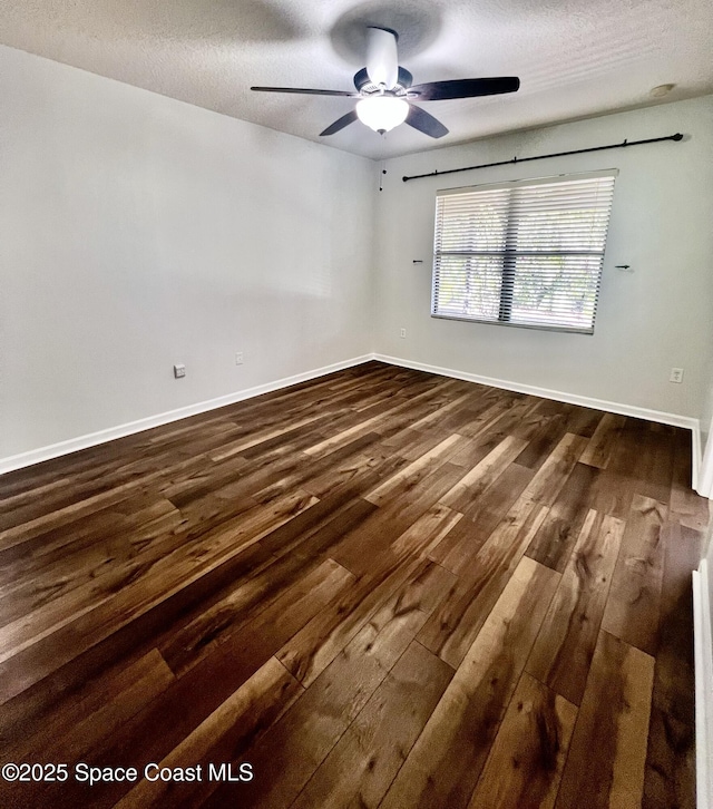 unfurnished room featuring a textured ceiling, dark wood-type flooring, baseboards, and a ceiling fan