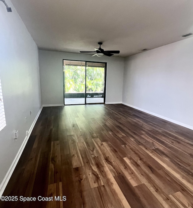 unfurnished room with ceiling fan, visible vents, baseboards, and dark wood finished floors