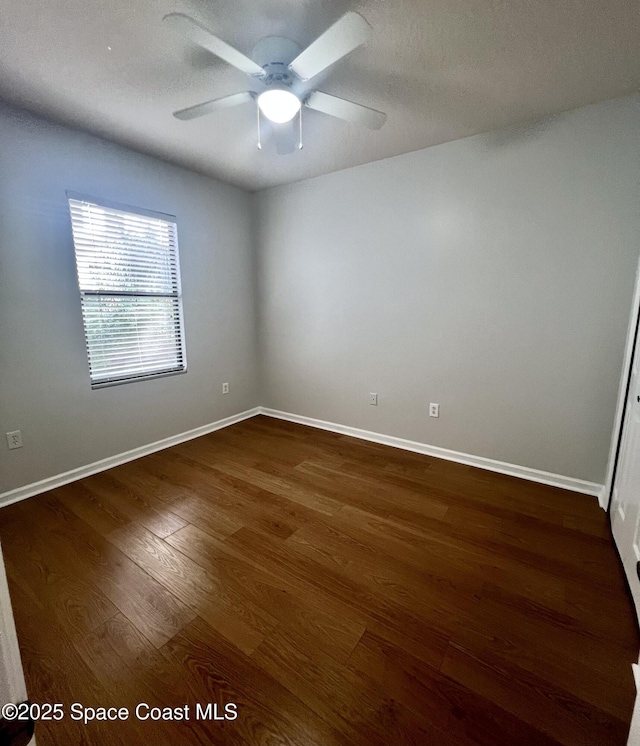 empty room featuring baseboards, a textured ceiling, dark wood finished floors, and a ceiling fan