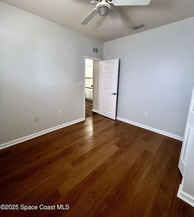 unfurnished bedroom with baseboards, visible vents, and dark wood-style flooring