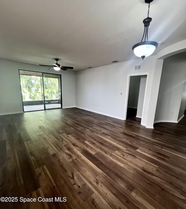 unfurnished living room featuring baseboards, visible vents, dark wood-style flooring, and ceiling fan