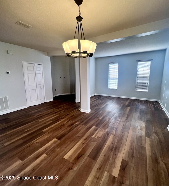 unfurnished dining area featuring a chandelier, visible vents, dark wood-type flooring, and baseboards