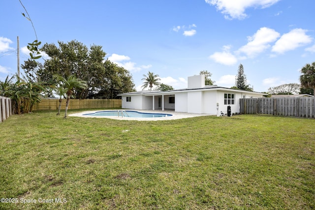 rear view of house featuring a yard, a fenced in pool, and a patio