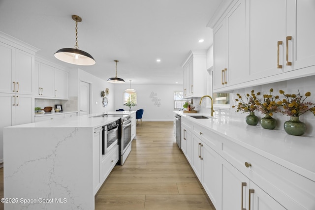 kitchen with white cabinetry, stainless steel appliances, decorative light fixtures, and sink