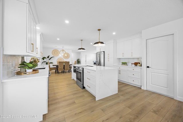 kitchen featuring stainless steel appliances, white cabinetry, and decorative light fixtures