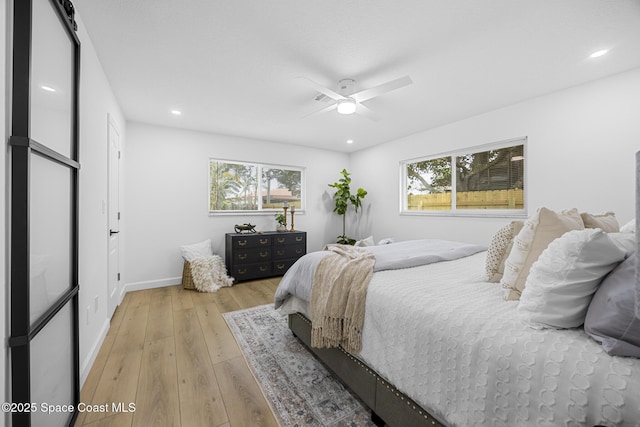 bedroom with ceiling fan, multiple windows, and light hardwood / wood-style flooring