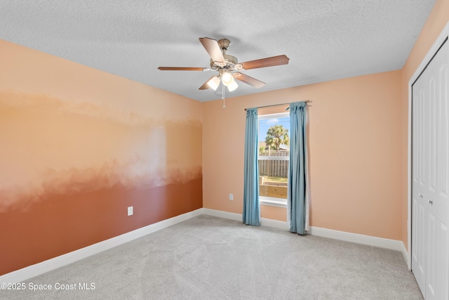 unfurnished bedroom featuring ceiling fan, light colored carpet, a closet, and a textured ceiling