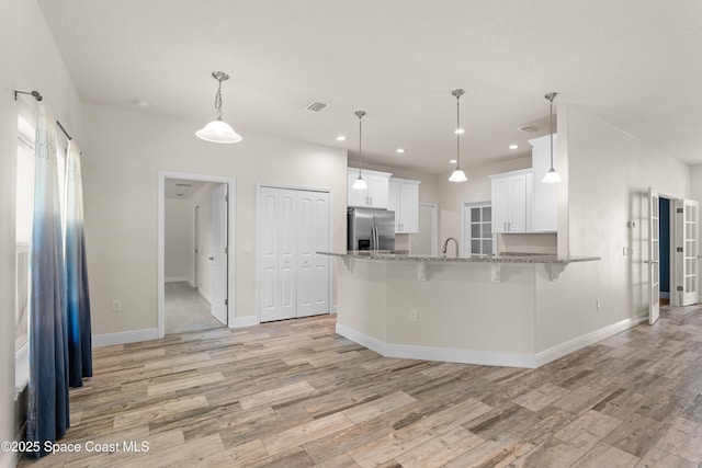 kitchen featuring stainless steel fridge with ice dispenser, decorative light fixtures, white cabinets, kitchen peninsula, and light wood-type flooring