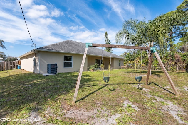 rear view of house featuring a playground, a yard, and central AC