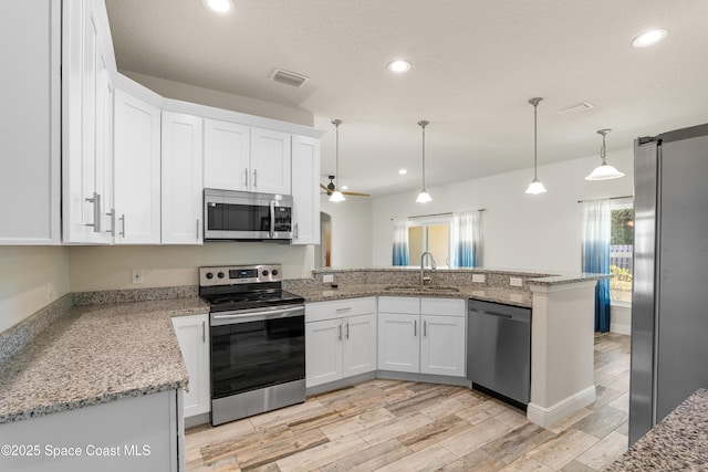 kitchen with white cabinetry, stainless steel appliances, decorative light fixtures, and kitchen peninsula