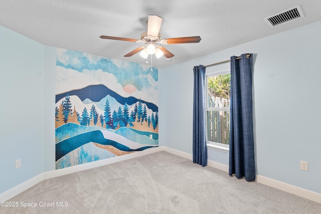 carpeted empty room featuring ceiling fan and a textured ceiling