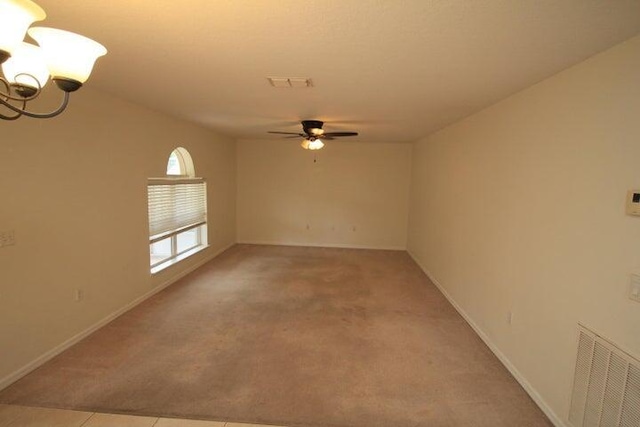 spare room with ceiling fan with notable chandelier and light colored carpet