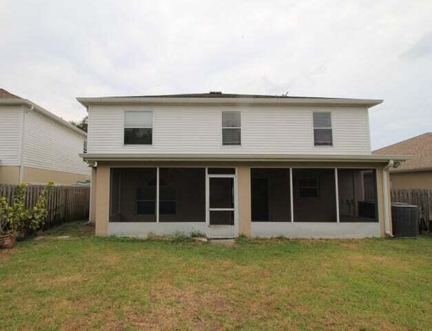 back of house with central AC unit, a sunroom, and a lawn