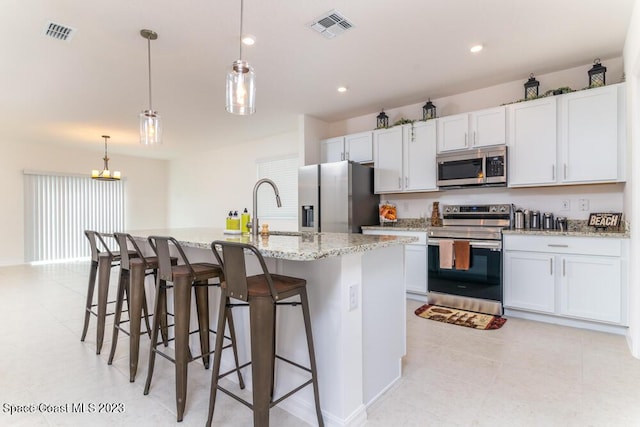 kitchen with white cabinetry, an island with sink, appliances with stainless steel finishes, and hanging light fixtures