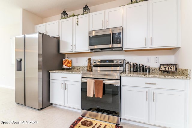 kitchen featuring light stone counters, stainless steel appliances, white cabinets, and light tile patterned flooring