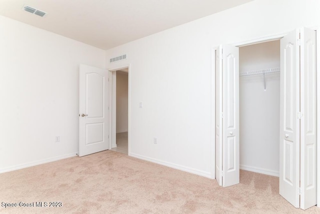 unfurnished bedroom with a closet and light carpet