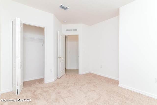 unfurnished bedroom with light colored carpet and a closet