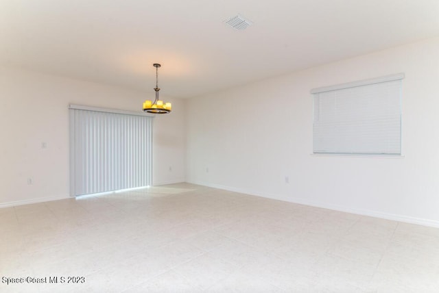 unfurnished room with a notable chandelier