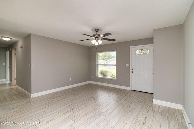 foyer entrance with light wood-style flooring, a ceiling fan, and baseboards