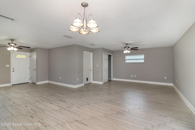 unfurnished living room with visible vents, baseboards, a textured ceiling, and light wood finished floors