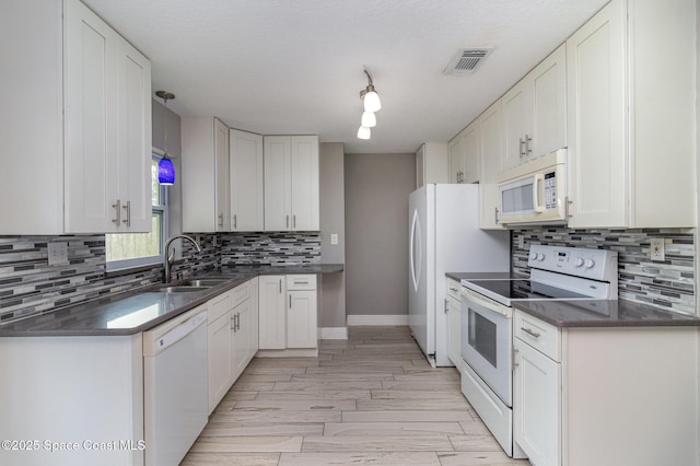 kitchen featuring white appliances, visible vents, a sink, white cabinetry, and tasteful backsplash