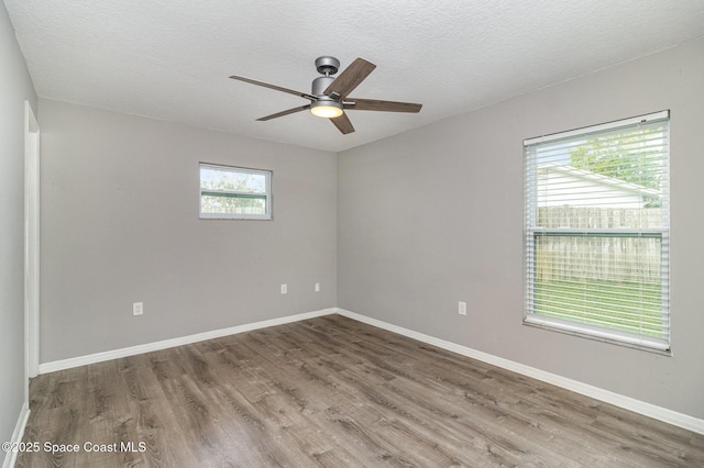 spare room featuring ceiling fan, baseboards, a textured ceiling, and wood finished floors