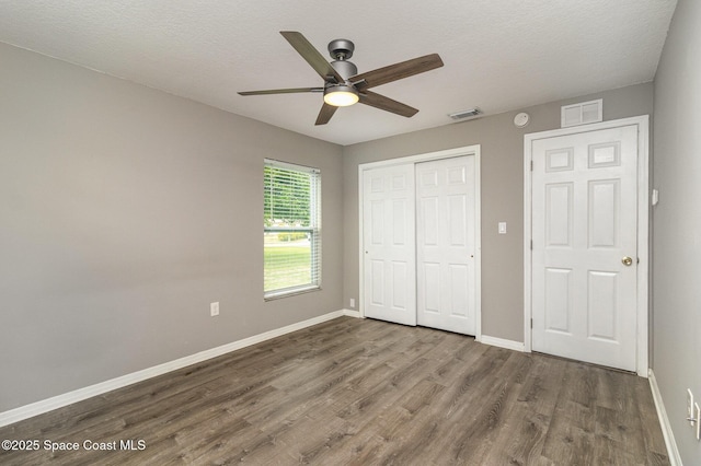 unfurnished bedroom with visible vents, baseboards, a closet, and wood finished floors