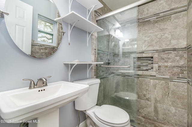 bathroom with a shower stall, toilet, and a sink