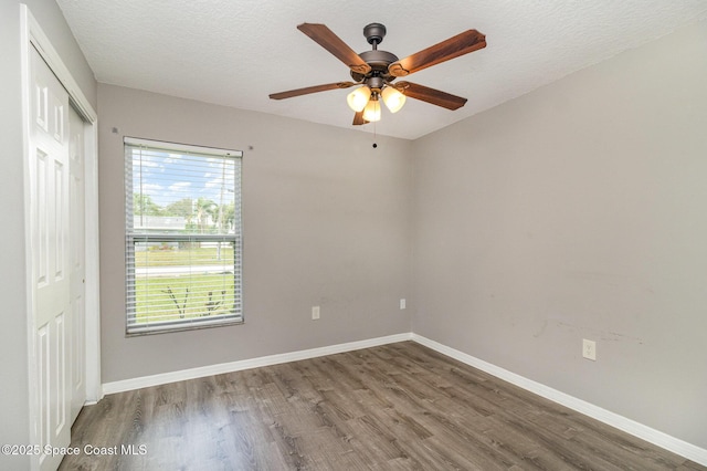 spare room featuring ceiling fan, a textured ceiling, baseboards, and wood finished floors