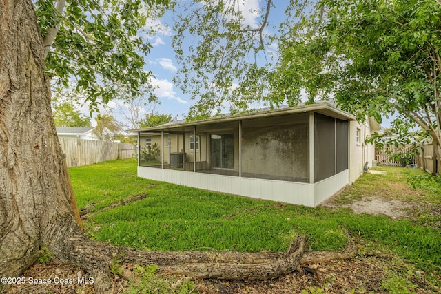 back of property with a lawn, a fenced backyard, and a sunroom