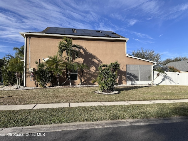 view of side of home with a yard and solar panels