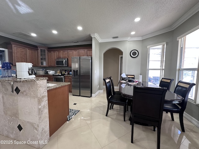 kitchen with ornamental molding, stainless steel appliances, and stone countertops