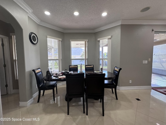 tiled dining room with crown molding and a textured ceiling