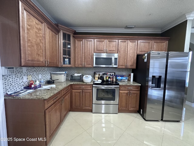 kitchen with crown molding, stainless steel appliances, backsplash, and light tile patterned floors