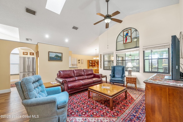 living room featuring hardwood / wood-style flooring, ceiling fan with notable chandelier, and high vaulted ceiling