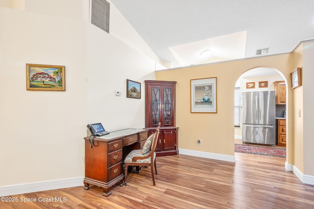 home office with wood-type flooring and vaulted ceiling