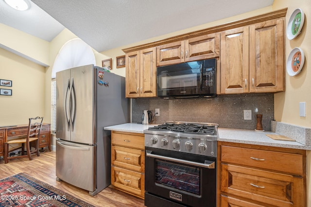 kitchen with stainless steel appliances, tasteful backsplash, and light hardwood / wood-style floors