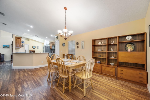 dining area featuring hardwood / wood-style flooring, lofted ceiling, a notable chandelier, and a textured ceiling