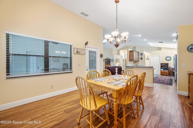 dining room featuring a notable chandelier, lofted ceiling, and light wood-type flooring